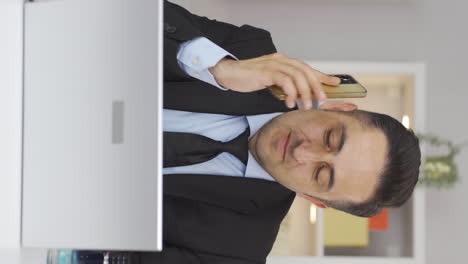 Vertical-video-of-Home-office-worker-man-getting-good-news-on-the-phone.
